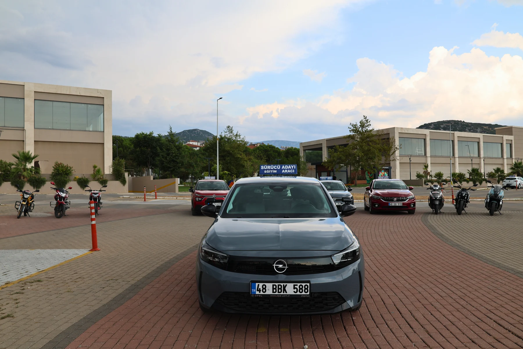 Şah Sürücü Kursu gri Opel ve arkasındaki eğitim araçları