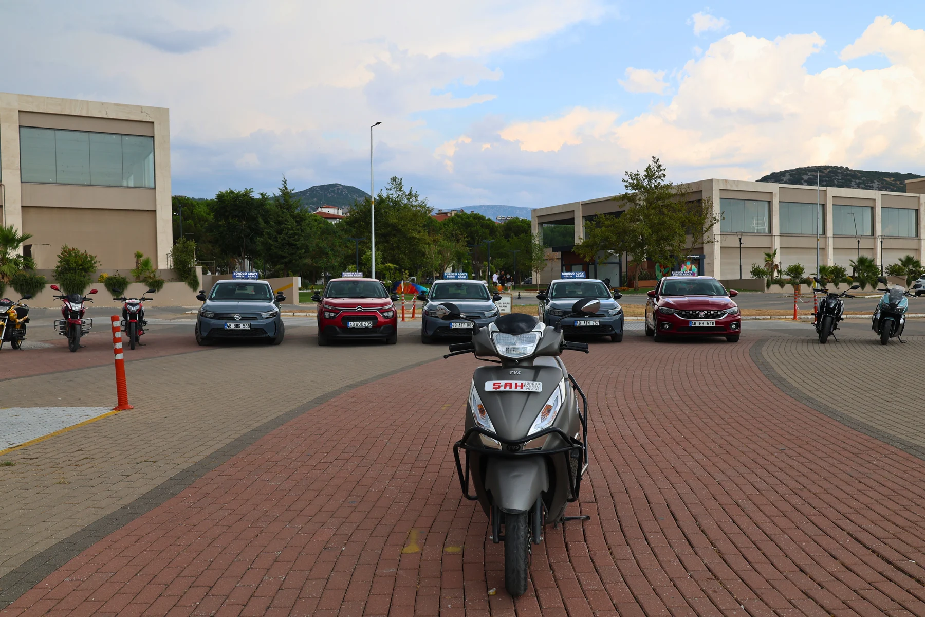 Şah Sürücü Kursu scooter motosikleti ve arkasındaki eğitim araçları