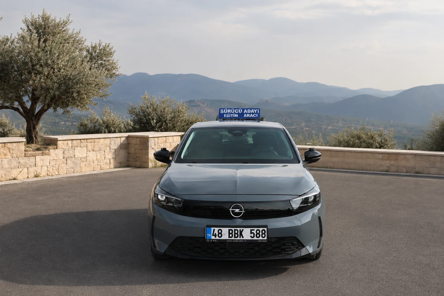 A gray Opel and other Şah Driving School training vehicles behind it